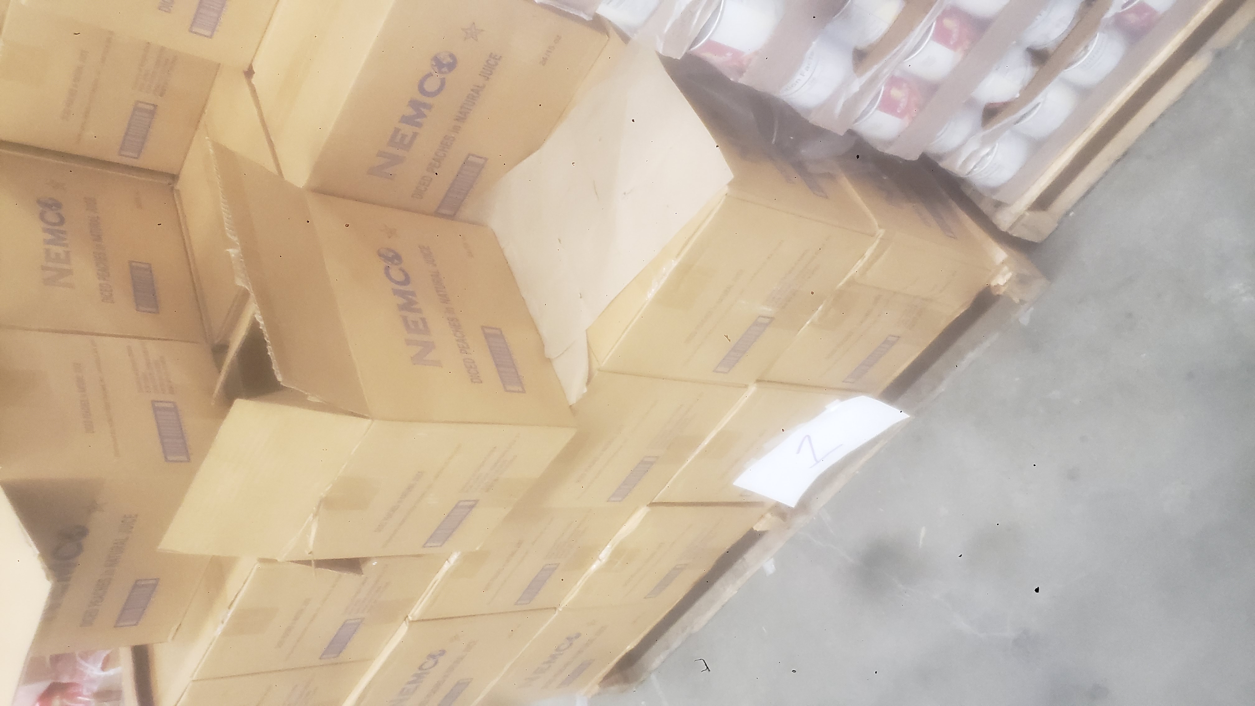 Boxes of canned diced peaches on a pallet.